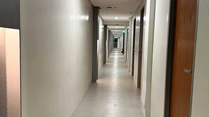 A long, narrow hotel corridor with doors on both sides, leading to individual rooms. - Townhouse Oak Nexgen Apartments & Hotel (Pasay)