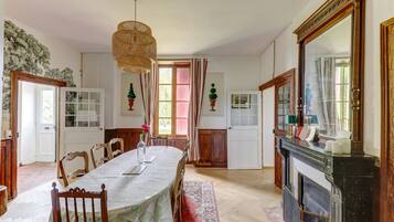 Comedor con una mesa larga, sillas, chimenea y un espejo grande.