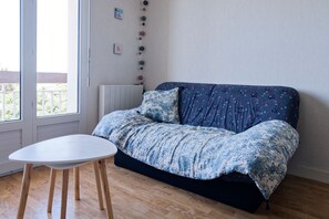 A room with a sofa, a small table, and a window. - La Bisquine Granvillaise - Appt 1 chambre proche de la plage (Granville)