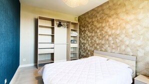 Een slaapkamer met een bed, een kledingkast en een nachtkastje.