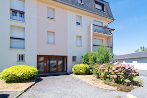 A multi-story residential building with a flat facade, a central entrance with a door, and a small balcony on the second floor. - La Bisquine Granvillaise - Appt 1 chambre proche de la plage (Granville)