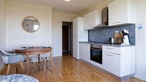 Een moderne keuken met witte kasten, een inbouwoven en een koffieapparaat.