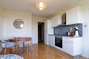 A modern kitchen with white cabinets, a built-in oven, and a coffee machine. - La Bisquine Granvillaise - Appt 1 chambre proche de la plage (Granville)