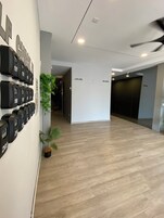 Un pasillo con un sistema de números en la pared, una planta en maceta y suelo de madera.