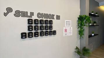 A wall with a self-check-in system and a QR code for walk-in guests.