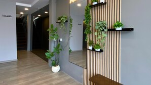 A hallway with a wooden bench, a mirror, and potted plants. - Muntri Inn by Soft Loft (George Town)