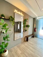 A hotel reception area with a large mirror, a bench, and potted plants.