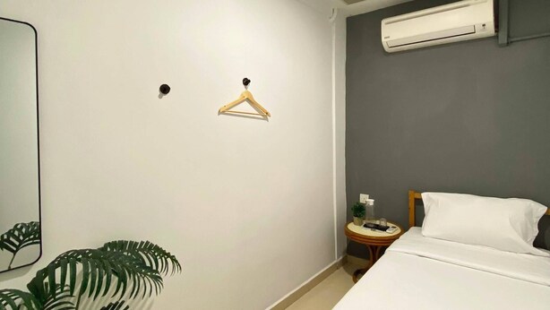 A hotel room with a bed, a bedside table with a lamp, a hanging plant, and an air conditioning unit. - Muntri Inn by Soft Loft (George Town)