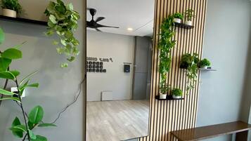 A hotel room with a large mirror, a ceiling fan, a wooden bench, and potted plants.