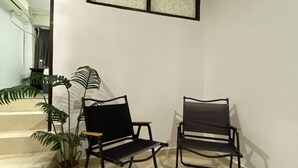 A room with two black metal-framed chairs, a potted plant, and a staircase leading to another area. - Muntri Inn by Soft Loft (George Town)