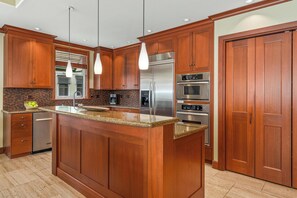 Eine moderne Küche mit Holzschränken, Edelstahlgeräten und einer Arbeitsplatte aus Granit.