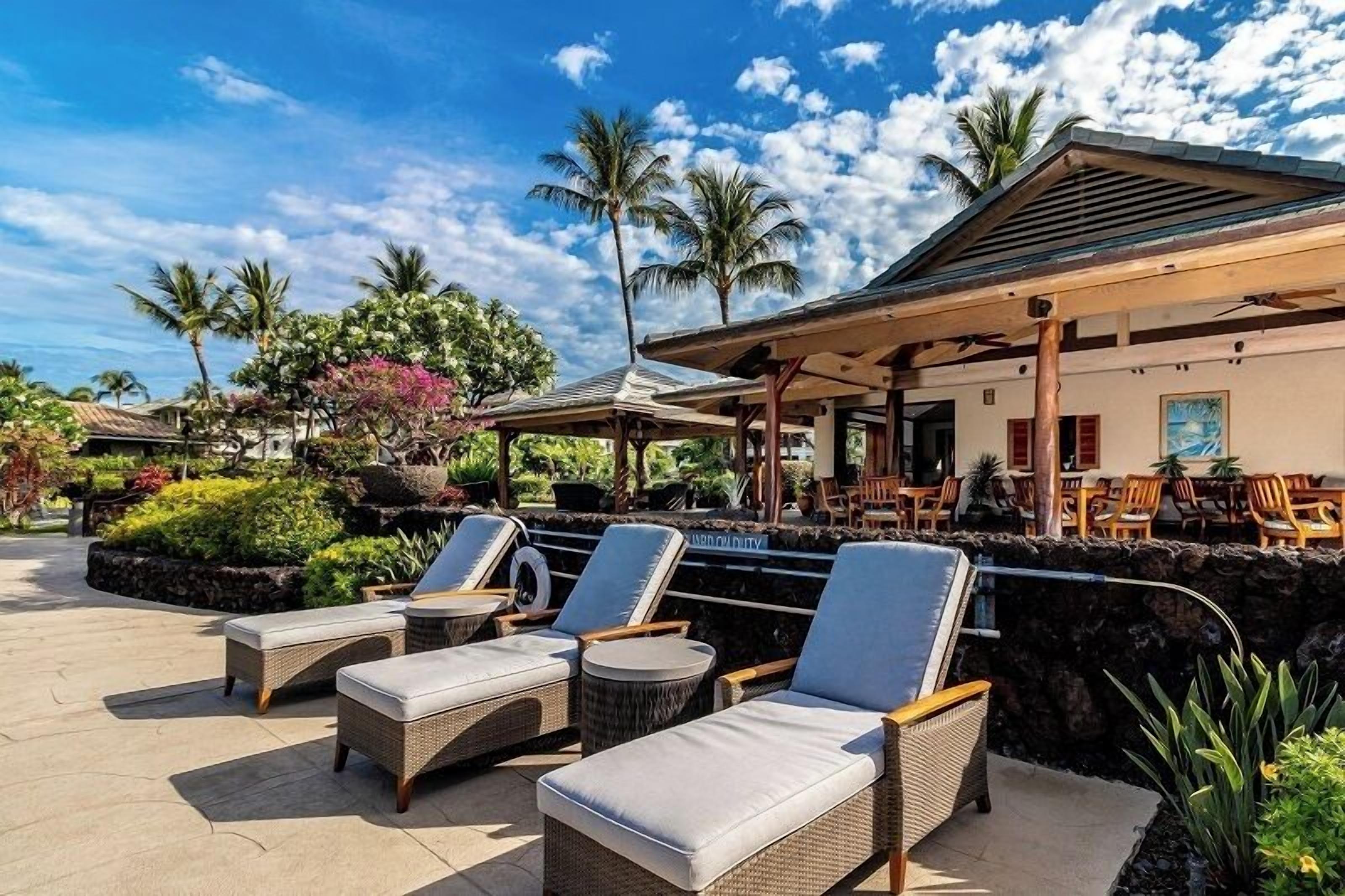 A resort with outdoor seating, palm trees, and a covered area.
