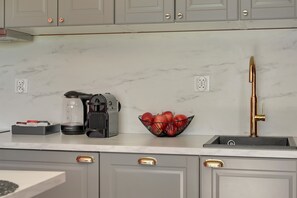 A kitchen with a coffee maker, a fruit bowl, and a sink with a faucet. - Rezydencja Wintera 1A | River View (Gdańsk)