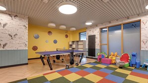 Ein Zimmer mit einem Pongtisch, farbenfrohem Teppich und verspielten Wanddekorationen.