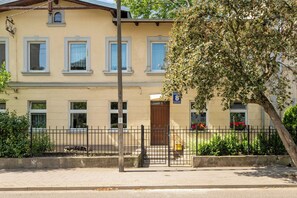 Ein zweistöckiges Gebäude mit gelber Fassade, zahlreichen Fenstern und einem gut sichtbaren Eingang.