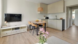 Een moderne keuken met een eethoek, een flatscreen televisie en een vaas met bloemen.