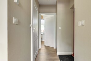 Ein Flur mit weißen Wänden, Holzdielen und einer Tür zu einem anderen Zimmer.