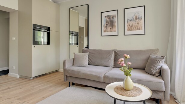 Een moderne woonkamer met een bank, een klein rond tafeltje en een bloevas.