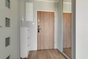 Ein Flur mit einer Holztür, einem weißen Wandtelefon und einem kleinen, weißen Schrank.