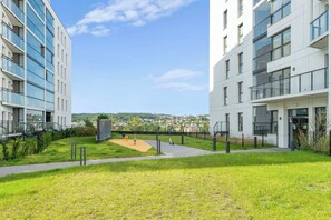 Ein moderner Gebäudekomplex mit einem zentralen Innenhof, der einen Spielplatz und eine Aussichtsplattform bietet.