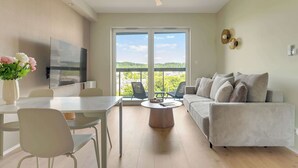 Ein modernes Wohnzimmer mit Flachbildfernseher, Esstisch, Stühlen, einer Couch und einem Deckenventilator.