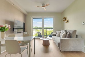 Ein modernes Wohnzimmer mit Flachbildfernseher, Esstisch, Stühlen, einer Couch und einem Deckenventilator.