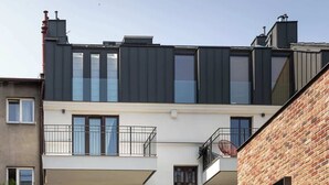 Un edificio residencial de varios pisos con balcones, un sendero de madera y fachada de ladrillo.