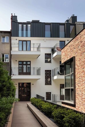 Ein mehrgeschossiges Wohngebäude mit Balkonen, einem Holzsteg und einer Ziegel-Fassade.