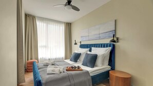 A hotel room with a bed, a bedside table, a wall-mounted lamp, and a ceiling fan. - Chlebova 4.19 | Motława River & Shipyard | Gym (Gdańsk)