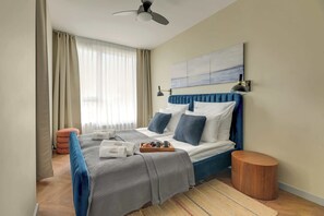 Ein Hotelzimmer mit einem Bett, einem Nachttisch, einer Wandlampe und einem Deckenventilator.