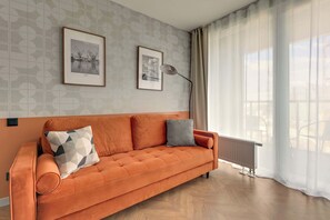 A modern living room with a sofa, two framed pictures, a floor lamp, and a radiator. - Chlebova 4.19 | Motława River & Shipyard | Gym (Gdańsk)