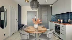 A modern kitchen with grey cabinets, a wooden dining table, and a hanging light fixture. - Chlebova 4.19 | Motława River & Shipyard | Gym (Gdańsk)