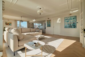 A modern living room with a beige sofa, a coffee table, and a view of the city through large windows. - 140sqm | Chlebova Penthouse | Riverview | Parking (Gdańsk)