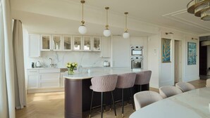 Una cocina moderna con encimeras de mármol, una isla central con taburetes altos e iluminación colgante.