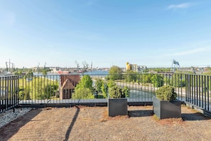 A balcony with a view of a river, industrial buildings, and a bridge. - 140sqm | Chlebova Penthouse | Riverview | Parking (Gdańsk)