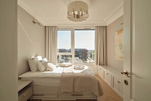 A bedroom with a large window, a bed with white bedding, a bedside table, and a view of the cityscape. - 140sqm | Chlebova Penthouse | Riverview | Parking (Gdańsk)
