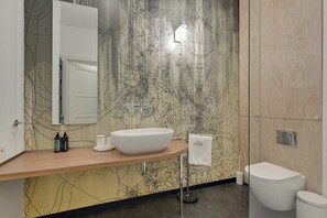 A modern bathroom with a large mirror, a white sink, and a toilet.