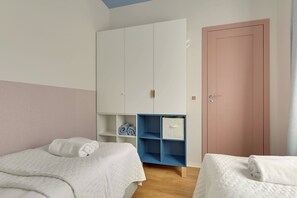 A bedroom with two beds, a wardrobe, and a door.