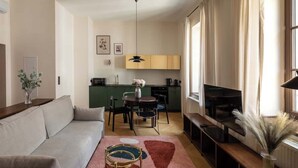 En kompakt bolig med sofa, spisebord, tekøkken og TV.