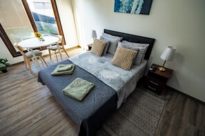 Una camera d'albergo con un letto, comodini, una sedia, un tavolino e vista sull'esterno.