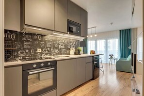 A modern kitchen with a chalkboard wall listing coffee options, a built-in oven, and a microwave. - Dwie Motławy 40 | Riverside | Balcony (Gdańsk)