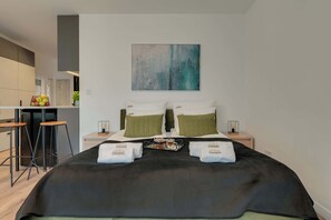 A hotel room with a bed, two nightstands, a bar area, and a large abstract painting on the wall. - Dwie Motławy 40 | Riverside | Balcony (Gdańsk)