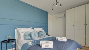 A bedroom with a bed, a nightstand, a wardrobe, and a hanging light fixture. - Letnicka 31 with Balcony | Perfect Stay (Gdańsk)