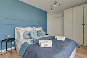 Ein Schlafzimmer mit Bett, Nachttisch, Kleiderschrank und einer Pendelleuchte.
