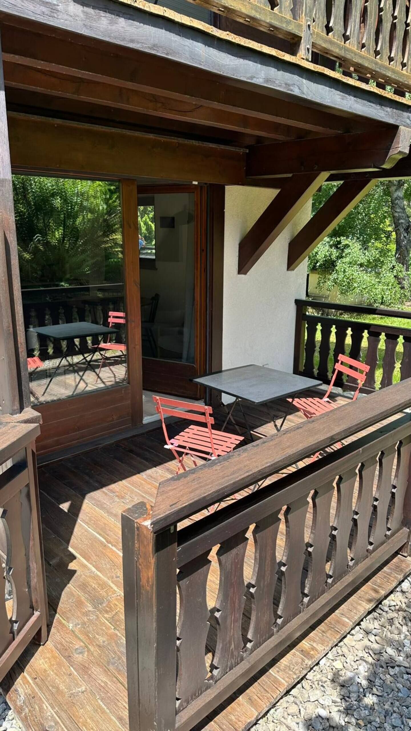 Un espace extérieur aménagé en terrasse, avec une plateforme en bois, une table et deux chaises.