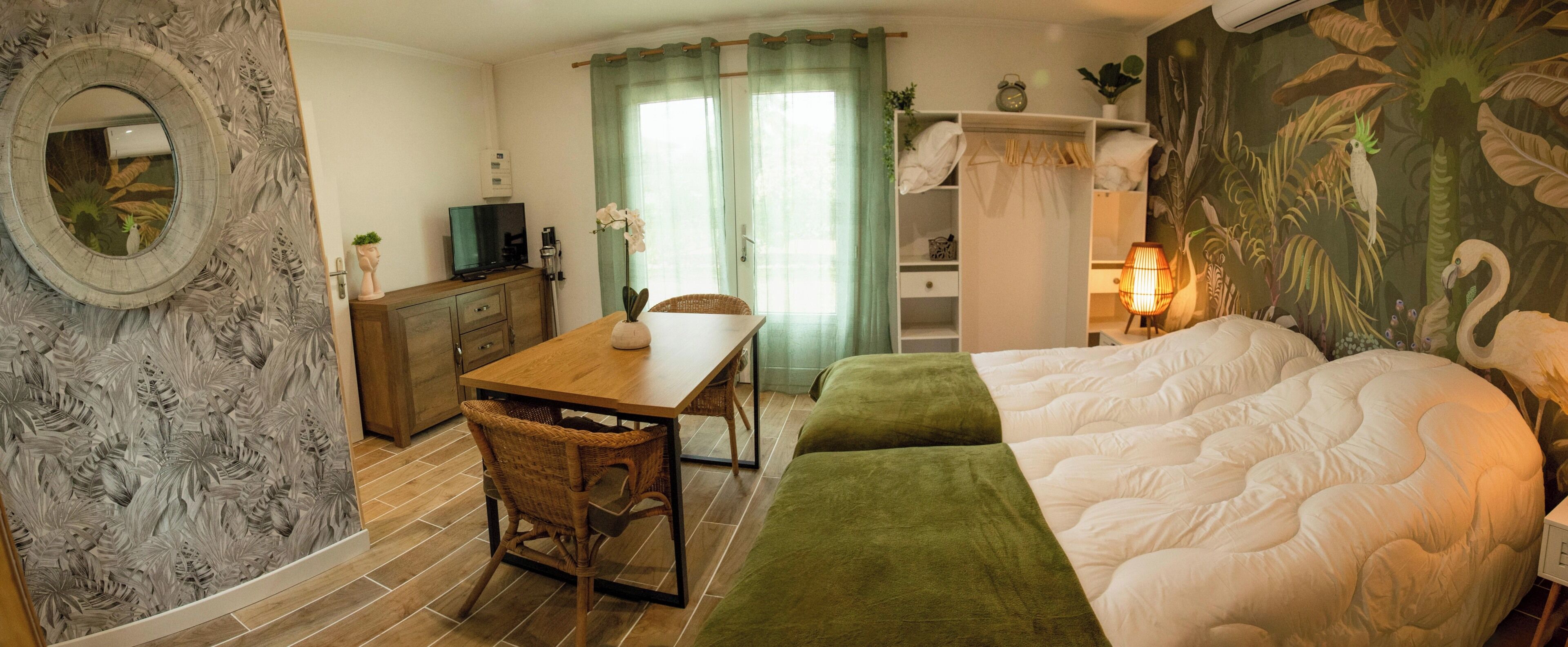 Una habitación de hotel con cama, escritorio, silla, televisor y espejo.