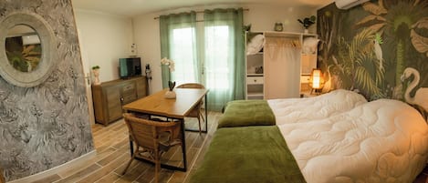 Una habitación de hotel con cama, escritorio, silla, televisor y espejo.