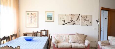 A dining area with a table and chairs, a sofa, and wall art.