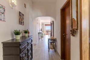 A hallway with a wooden cabinet, potted plants, a decorative mirror, and a door with a brass handle. - #386 Comfortable Stay in Montechoro | 2 Bedrooms (Albufeira)