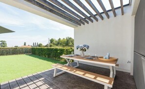 An outdoor patio with a wooden table set for dining, a bench, and a pergola overhead. - Alegria Newport - comfort, nature & coast in 6 min (Koksijde)
